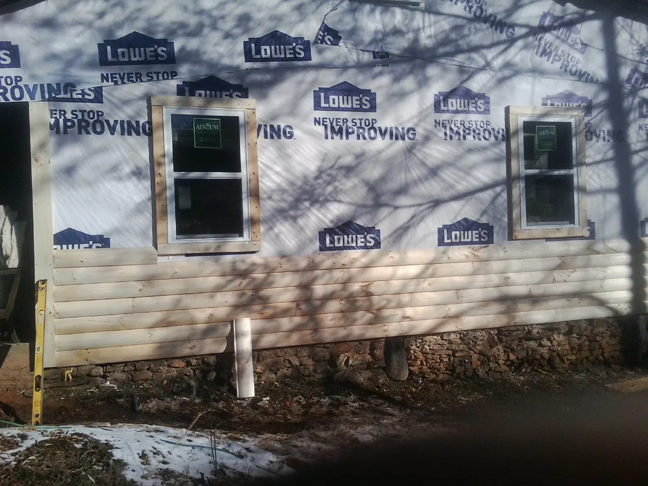 House wrap and new log siding going up on an exterior wall in Parker